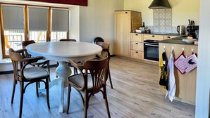 A modern kitchen with wooden cabinets, a built-in oven, and a large window. - Ferienwohnung mit Beheizten Pool bis 5 Personen (Marsaz)