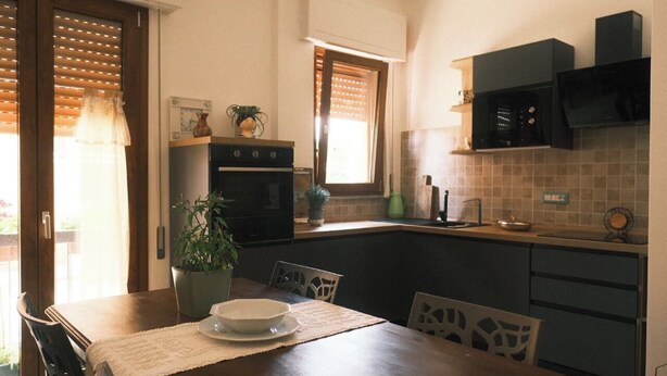 A compact kitchen with a dining area, featuring a built-in oven, microwave, and a small sink.
