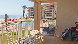 A balcony with a view of the beach, pool, and hotel buildings. - Second floor three bedroom three bath direct oceanfront (New Smyrna Beach)