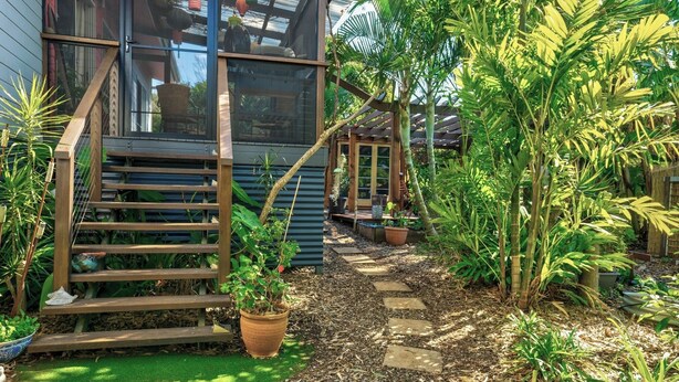 A garden pathway leading to a wooden staircase with a potted plant. - Enchanted Garden Island Cottage with Bikes and Air Con. (Russell Island)