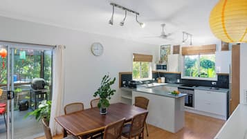 Een moderne keuken met een centraal eiland, witte kastjes en uitzicht op groen.
