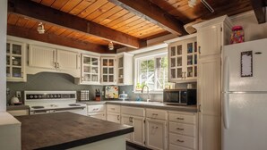 A kitchen with white cabinets, a stove, a microwave, and a refrigerator. - The Lake House  - Beachfront w/ Hot tub available! (Arnold)