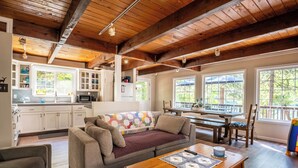 A cozy living room with a sofa, a wooden coffee table, and a dining area with a table and chairs. - The Lake House  - Beachfront w/ Hot tub available! (Arnold)
