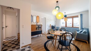 A modern living space with a dining area, a sofa, and a TV.