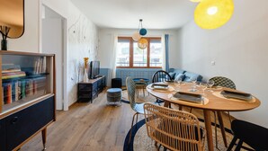 A modern dining area with a round wooden table, wicker chairs, and a blue sofa.
