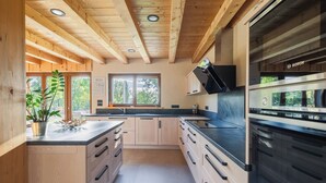 Cozinha moderna com vigas de madeira, um forno Bosch e uma grande janela.