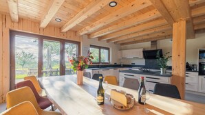 Interior de madeira com uma mesa de jantar posta para dois, uma garrafa de vinho e um copo.
