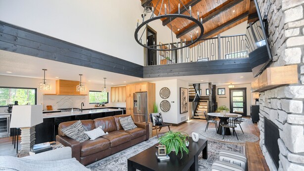 A spacious living area with a high ceiling, a kitchen, and a dining area. - Modern Spacious Cabin in Powder House w/ Hot Tub, Clubhouse Access to Pools! (Lead)