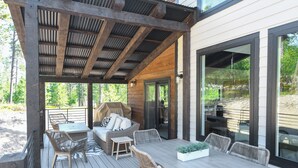 A covered outdoor patio with wicker furniture, a table, and a grill. - Modern Spacious Cabin in Powder House w/ Hot Tub, Clubhouse Access to Pools! (Lead)