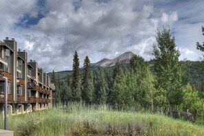 A modern building with balconies, surrounded by a natural landscape with tall trees and a mountain in the background. - North Star | Pool, Hot Tub, Ski Shuttle & Views - Tennis, Fireplace, Deck (Durango)