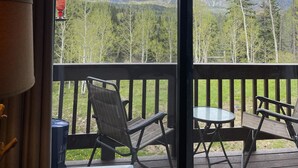 Een terras met twee stoelen en een tafel, uitkijkend op een bergachtig landschap met bomen.