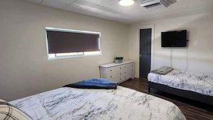 Une chambre avec deux lits, une commode, un téléviseur et un appareil de climatisation.