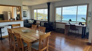 Amplia sala de estar con una mesa de comedor de madera, un sofá y vista al océano.