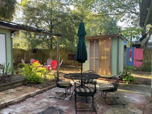Eine Terrasse mit Tisch und Stühlen, umgeben von Pflanzen und einem Holzzaun.