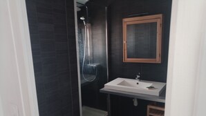 Een badkamer met een douche, wastafel en spiegel.