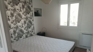 Een slaapkamer met een bed, nachtkastje, foto aan de muur en een raam.