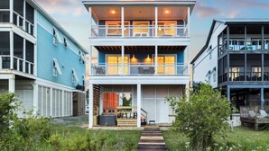 A two-story building with a balcony on the upper floor, a covered porch on the ground floor, and a wooden deck leading to the entrance. - Beachfront Home w/ Private Boardwalk (Port St. Joe)
