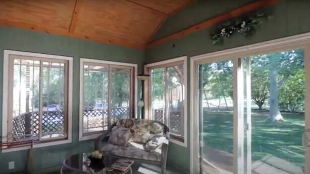 Una stanza con soffitto in legno, un divano, un tavolo e ampie finestre vista esterna.