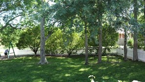 Un prato verdeggiante con alberi e un recinto bianco.