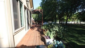 Un patio in legno con piante in vaso e altalene in giardino.