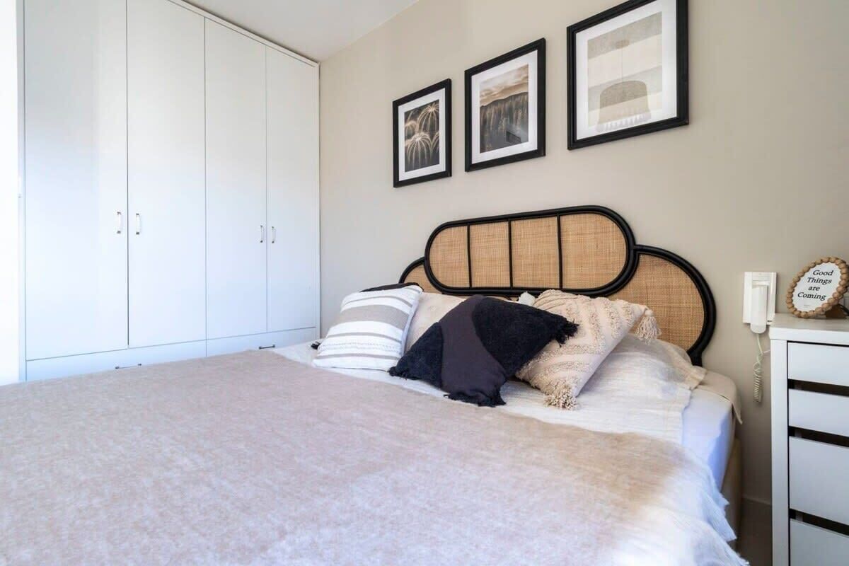 A bedroom with a bed, a wardrobe, and three framed pictures on the wall.