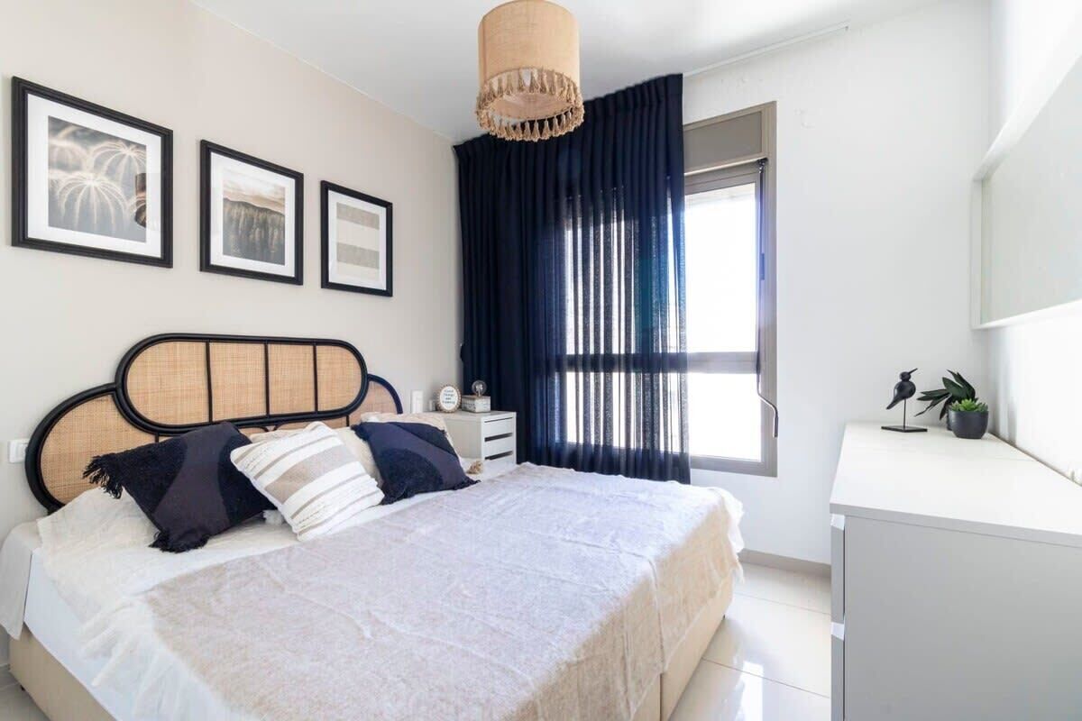 A bedroom with a bed, bedside table, and a window with curtains.
