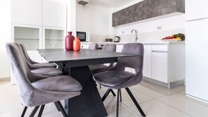 Une cuisine moderne avec une table et des chaises, des meubles blancs et un pare-feu gris.