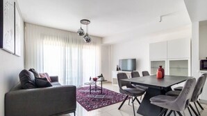 Un salon moderne comprenant un canapé, une table à manger, des chaises et un téléviseur.