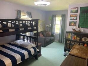 Um quarto com beliches, um sofá, uma estante de livros e um mapa na parede.