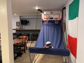 Ein Zimmer mit einer blauen Rutsche, einem Basketballkorb und einem Essbereich mit Stühlen und einem Tisch.