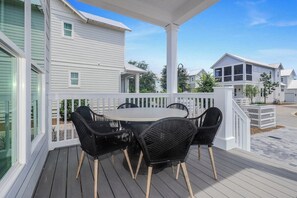 A covered outdoor area with a round table and black chairs, surrounded by white railings. - Santa Rosa Beach Blonde~ New with Elevator (Santa Rosa Beach)