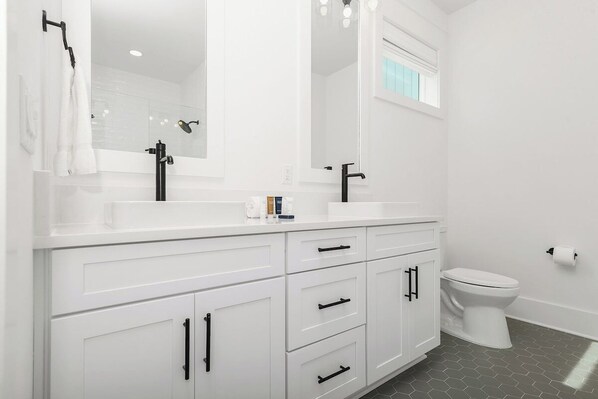 A modern bathroom with white cabinetry, a large mirror, a black faucet, and a toilet. - Santa Rosa Beach Blonde~ New with Elevator (Santa Rosa Beach)