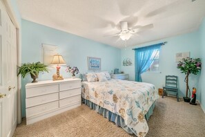 Une chambre à coucher comprenant un lit, une commode, un ventilateur de plafond et des objets décoratifs.