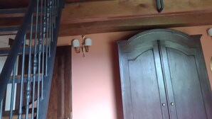 Un escalier avec une main courante en bois et des balustres en métal, menant à un balcon doté d’une rambarde.