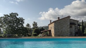 Un bâtiment en pierre avec une piscine devant.