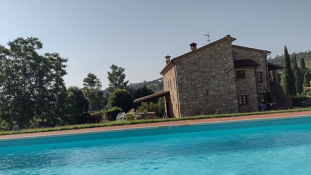 Un bâtiment en pierre avec une piscine devant.