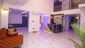 A modern hotel lobby with a reception desk, a plush orange sofa, and a large potted plant. - Akafia's Court (Accra)