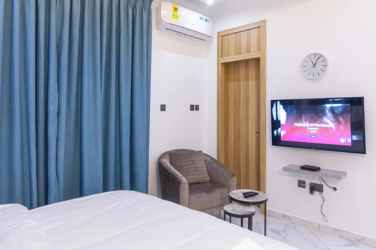 Une chambre d’hôtel avec un lit, une chaise, une télévision et une petite table.