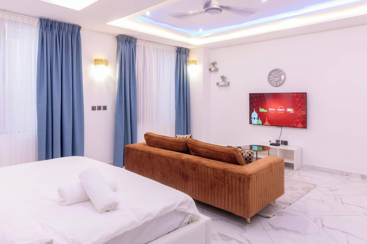 Une chambre d’hôtel moderne équipée d’un lit, d’un canapé, d’une télévision et d’un ventilateur de plafond.