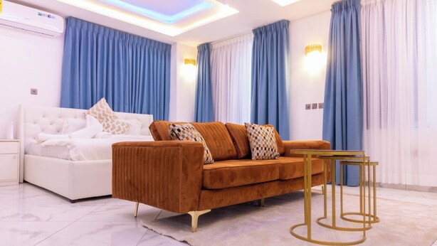 A modern living room with a white sofa, a brown sofa, and a small table with gold legs. - Akafia's Court (Accra)