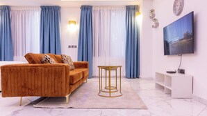 A modern living room with a sofa, a TV, and a small table. - Akafia's Court (Accra)