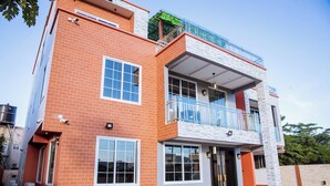 A two-story building with a brick facade, large windows, and a balcony with a metal railing. - Akafia's Court (Accra)