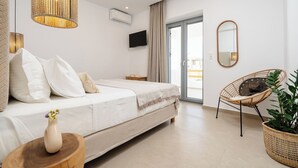 Ein modernes Schlafzimmer mit einem Bett, einem Fernseher, einem Spiegel und einem Korbsessel.