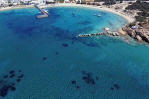 An aerial view of a coastal area with clear blue waters, a pier, and a sandy beach. - Nymphée - Callisti, Luxury Villa (Naxos)