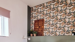 Una cama bien tendida con una bandeja de alimentos para el desayuno, un papel tapiz estampado y una lámpara colgante.