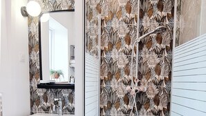 Un baño con ducha, lavamanos y espejo.