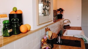 Una cocina con encimera de madera, un fregadero y varios utensilios de cocina, incluyendo un tarro de limones, un frasco de hierbas y un bol de naranjas.