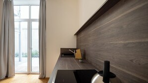 A modern kitchen with a black countertop, a stainless steel kettle, and a wooden sideboard.