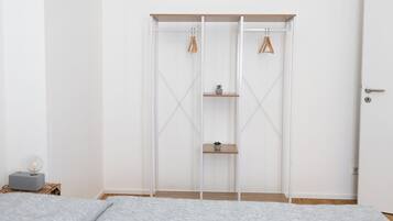 A bedroom with a bed, a wardrobe with shelves, and a bedside table with a lamp.