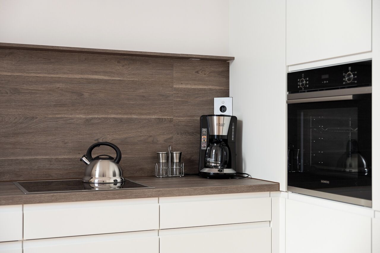 Eine moderne Küche mit Wasserkocher, Kaffeemaschine und Backofen.